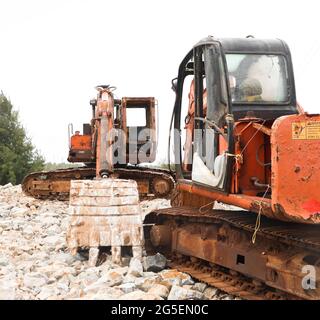 les excavatrices de bulldozer rouillées à l'orange sur le chantier effectuent des travaux de construction pendant l'après-midi dans un terrain stérile Banque D'Images