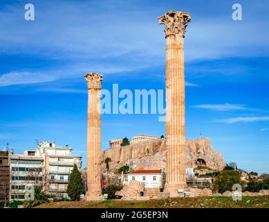 Athènes, Grèce : deux des colonnes restantes du Temple de Zeus olympique avec les Acopolis en arrière-plan. Banque D'Images