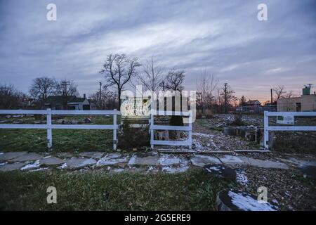 Un panneau à l'entrée d'un jardin communautaire indique « Hope prend racine ». Des bâtiments abandonnés, brûlés et clôturés dans le quartier de Corktown à Detroit. Beaucoup de lots sont lentement transformés en jardins communautaires et en espaces verts. Banque D'Images