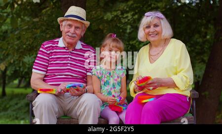 Grand-père de grand-mère senior souriant avec petite-fille jouant le jeu de jouet anti-stress de compression Banque D'Images