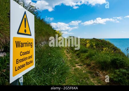 Un signe d'avertissement sur l'érosion côtière et les rochers lâches sur un chemin près de Montrose, en Écosse Banque D'Images