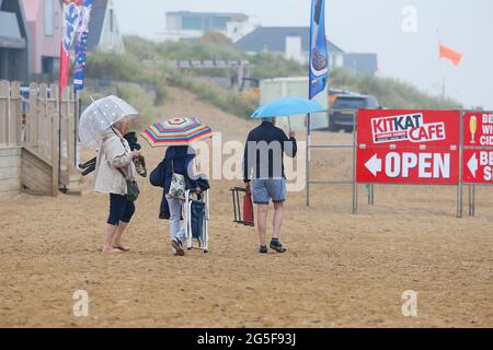 Camber, East Sussex, Royaume-Uni. 27 juin 2021. Météo au Royaume-Uni : le temps pluvieux attendu plus tard est arrivé tôt sur les plages de sable de Camber Sands dans l'est du Sussex. Certaines familles ont l'intention de profiter de la journée lorsqu'elles arrivent avec des parasols et des ponchos de pluie. Crédit photo : Paul Lawrenson /Alay Live News Banque D'Images