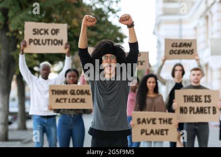 Black Guy leader du groupe international de protestants, hissant des poings, des gens du millénaire de différentes nationalités tenant des placards et des chanti Banque D'Images