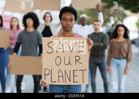 Black Woman holding étiquette avec sauver notre planète texte, groupe multiracial leader de personnes millénaires frappant dans la rue contre la pollution, vert Banque D'Images
