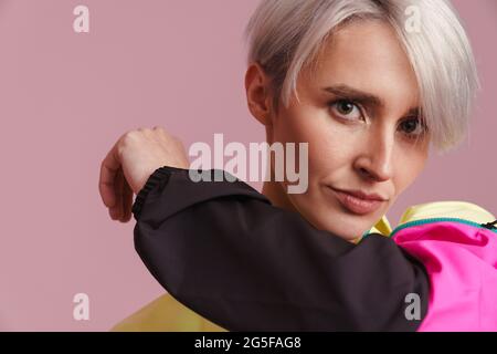 Femme aux cheveux blancs posant dans une veste multicolore isolée sur un mur violet Banque D'Images