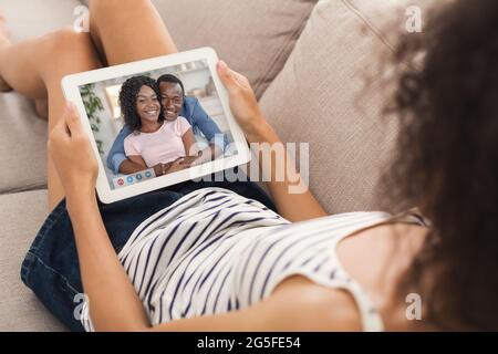 Communication à distance pendant une pandémie de covid. Une jeune femme se réunit avec un couple noir positif sur une webcam, en utilisant une tablette pc pour parler à ses amis o Banque D'Images