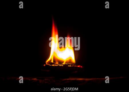 Gros plan de Diva ou divida en feu, de Diya ou de lampe à huile isolée dans l'obscurité. Banque D'Images