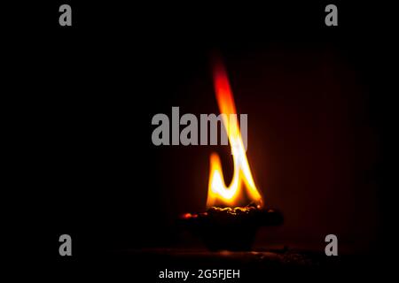 Gros plan de Diva ou divida en feu, de Diya ou de lampe à huile isolée dans l'obscurité. Banque D'Images