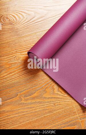 Un tapis de yoga lilas est torsadé sur le parquet. Mode de vie sain, sport Banque D'Images