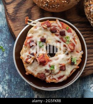 En haut, vue rapprochée d'un bagel à pizza chorizo fait maison sur une planche de bois. Banque D'Images