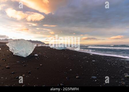 Blocs de glace sur une plage de sable noir au coucher du soleil Banque D'Images