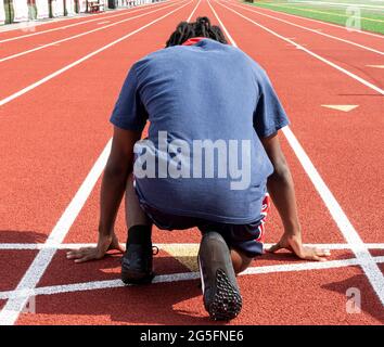 Vue arrière d'une piste d'école secondaire et d'un coureur de sprint prêt à courir sur la piste pendant l'entraînement. Banque D'Images