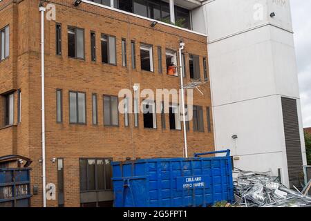 Maidenhead, Berkshire, Royaume-Uni. 11 juin 2021. Un constructeur jette les raccords d'un bloc de bureau qui doit être démoli. Maidenhead subit une importante régénération malgré la pandémie de Covid-19. De nombreux appartements de luxe sont en construction dans la ville car les prix de l'immobilier continuent d'augmenter à un rythme alarmant. Crédit : Maureen McLean/Alay Banque D'Images