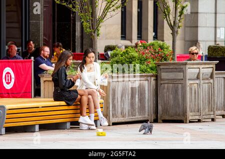 Dundee, Tayside, Écosse, Royaume-Uni. 27 juin 2021. Météo au Royaume-Uni : une belle journée sèche avec de nombreuses vagues lumineuses et ensoleillées qui apparaissent tout au long de l'après-midi dans le nord-est de l'Écosse avec des températures atteignant 20°C. Beaucoup de gens sont encore bien conscients des directives de distanciation sociale et le port de masques de visage que les résidents locaux prennent la journée pour profiter du temps et de socialiser dehors. Deux jeunes femmes à la mode se réunissent pour s'asseoir et déguster quelque chose à manger un dimanche après-midi dans le centre-ville de Dundee. Crédit : Dundee Photographics/Alamy Live News Banque D'Images