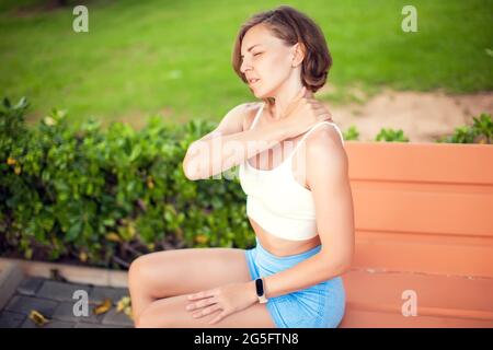 Douleurs au cou. Femme qui ressent une douleur au cou ou à l'épaule à l'extérieur. Concept de soins de santé et de mode de vie Banque D'Images