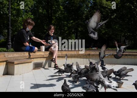 Varsovie, Varsovie, Pologne. 27 juin 2021. Les enfants nourrissent des pigeons assis au bord d'une fontaine vide le 27 juin 2021 à Varsovie, en Pologne. Crédit: Aleksander Kalka/ZUMA Wire/Alay Live News Banque D'Images