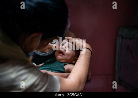 New Delhi, Inde. 27 juin 2021. Un travailleur de la santé administre une dose de vaccin contre la polio à un enfant dans le cadre d'un programme national de vaccination contre la polio impulsionnelle (PPI) dans un bidonville de Darya Ganj. L'OMS, l'UNICEF, le Rotary et d'autres organisations de la société civile mènent une campagne de vaccination à grande échelle contre la polio de juin 27 à juin 29 2021 dans toute l'Inde, plus de 110 millions (mn) d'enfants de moins de cinq ans seront vaccinés contre la polio au cours des trois jours. Crédit : SOPA Images Limited/Alamy Live News Banque D'Images