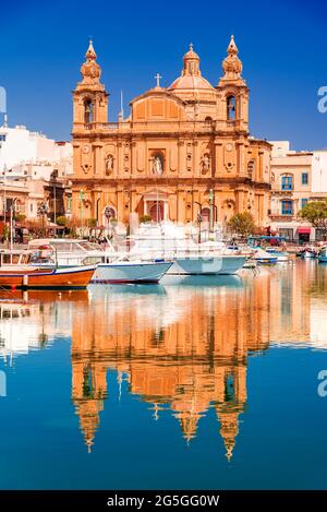 La Valette, Malte. Le bateau Msida Marina et l'église Saint-Joseph se reflètent dans l'eau. Banque D'Images