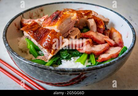 Rôti de canard cantonais avec rôti de porc au miel et légumes verts dans un arc avec du riz. Banque D'Images