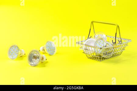 Lampes LED à économie d'énergie dans un panier en métal sur fond jaune. Banque D'Images