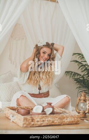 Une jeune femme se détendant dans un hôtel tropical de luxe ou une villa privée. Femme parfaite avec des cheveux blonds bouclés souriants Banque D'Images