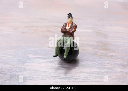 Un gros plan de la figurine d'une petite personne avec des mains croisées sur une balle noire Banque D'Images