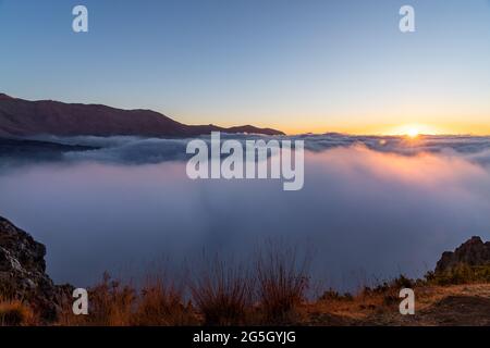 Vue magnifique sur un coucher de soleil derrière des nuages blancs doux dans les Hautes montagnes. Vue imprenable sur le coucher du soleil entre les cieux. Beauté de la nature. Banque D'Images