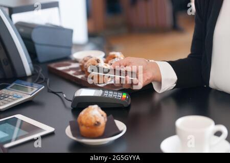 Faire du paiement sans contact dans un café avec téléphone mobile une tendance croissante avec téléphone mobile tenu près du lecteur de carte Banque D'Images