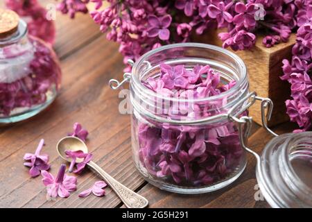 Fleurs de lilas dans un pot, une bouteille d'huile ou de perfusion, bouquet de fleurs de Syringa. La préparation de la perfusion, du sucre aromatique ou de la confiture de fleurs lilas au hom Banque D'Images