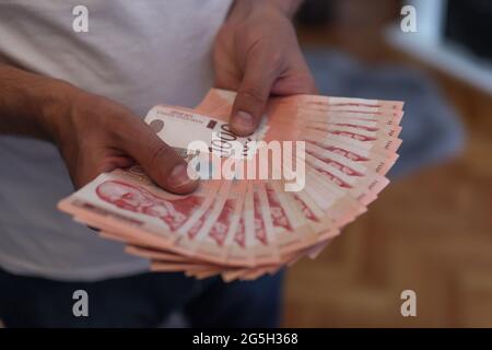 Mains de sexe masculin tenant une pile d'argent. Monnaie de papier dinar serbe, valeur de 1000 dinars Banque D'Images