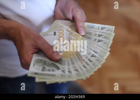 Mains de sexe masculin tenant une pile d'argent. Monnaie de papier dinar serbe, valeur de 2000 dinars Banque D'Images