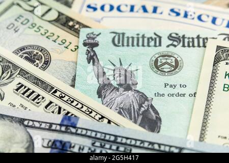 Vue macro de la Statue de la liberté sur un chèque du Trésor des États-Unis avec carte de sécurité sociale en arrière-plan. Banque D'Images
