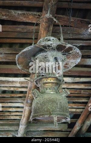 vieille lampe à kérosène accrochée au plafond d'une maison rurale couverte de toile d'araignées Banque D'Images