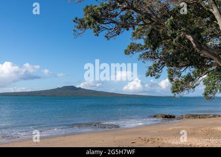 L'île Rangitoto se trouve à un horizon lointain, en face du port, de la plage de St Leonard, sur la rive nord d'Auckland. Banque D'Images