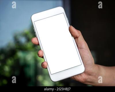 Image maquette du téléphone. Gros plan blanc écran vierge sur le téléphone portable en main. Main tenant un smartphone blanc avec écran vide. Banque D'Images
