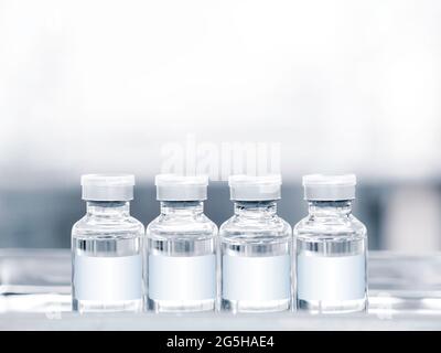 Flacons de vaccins médicaux avec étiquette blanche vierge sur le plateau avec espace de copie. Image en gros plan de quatre flacons de vaccin en verre pour injection. Banque D'Images