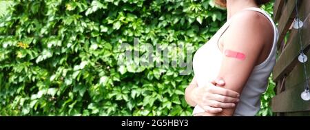 Banner. Femme avec un plâtre sur sa main se réjouit de recevoir une vaccination contre le coronavirus Covid-19 Banque D'Images