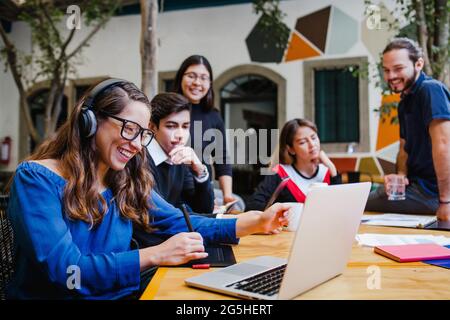 Jeune femme d'affaires latine souriante et personnes ayant des réunions d'affaires en ligne sur le lieu de travail au Mexique Banque D'Images