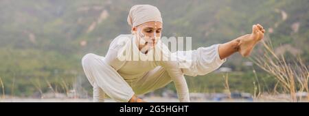 BANNER, LONG FORMAT Kundalini yoga femme en vêtements blancs et le turban pratique le yoga kundalini sur le fond de la mer, les montagnes et le coucher du soleil Banque D'Images