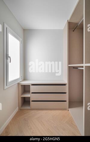 Nouveau mobilier intégré dans un petit dressing. Espace de rangement moderne et vide avec armoire, tiroirs et beaucoup d'espace pour les cintres. Banque D'Images