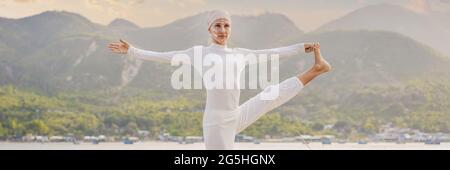 BANNER, LONG FORMAT Kundalini yoga femme en vêtements blancs et le turban pratique le yoga kundalini sur le fond de la mer, les montagnes et le coucher du soleil Banque D'Images