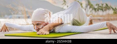 BANNER, LONG FORMAT Kundalini yoga femme en vêtements blancs et le turban pratique le yoga kundalini sur le fond de la mer, les montagnes et le coucher du soleil Banque D'Images