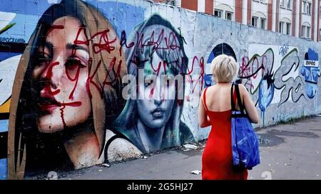 Moscou, Russie. 25 juin 2021. Une femme passe devant un graffiti vandalisé.la chaleur anormale à Moscou a duré une semaine du 21 au 28 juin 2021. La température à Moscou de juin 22 à juin 27 a dépassé de 1.6 degrés le précédent record et atteint plus 33.6, a déclaré Roman Vilfand, directeur scientifique du Centre hydrométéorologique. ''la température a été fixée à 33.6 degrés, et elle ne sera pas plus élevée, '' dit Vilfand. Le météorologue a rappelé que le précédent record de température a été atteint le 27 juin 2013 et qu'il était de 32 degrés. Crédit : Mihail Tokmakov/SOPA Images/ZUMA Wire/Alay Live News Banque D'Images