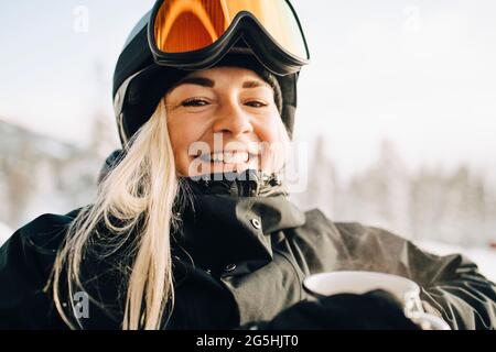 Portrait d'une femme blonde souriante portant des lunettes de ski et un casque Banque D'Images