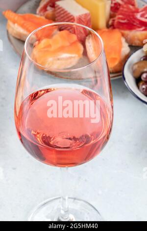 Un verre de vin rose avec des sandwiches au saumon et des fromages. Tapas espagnoles dans un bar. Un gros plan d'un verre d'été lors d'une fête Banque D'Images