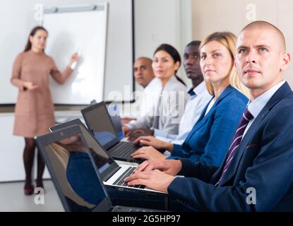 Vue latérale du groupe de managers travaillant sur des ordinateurs portables au bureau Banque D'Images