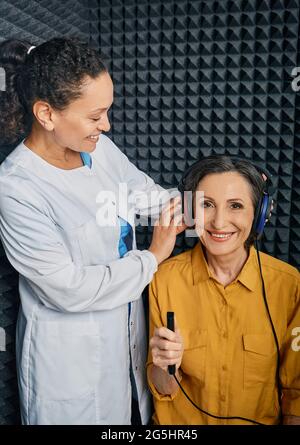 Examen audiométrique. Audiologiste effectuant un contrôle auditif auprès d'une femme mature dans une cabine audiométrique insonorisée. Test d'audiogramme à tonalité pure Banque D'Images