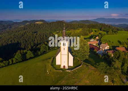 Sveti Andrej, Slovénie - vue aérienne par drone de l'église Saint Andrew (SV. Andrej) au coucher du soleil dans la région de Skofja Loka. Heure d'été dans les alpes slovènes avec c Banque D'Images