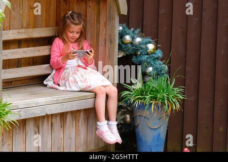 Une fille de 5 ans regardant des vidéos sur un téléphone portable Banque D'Images