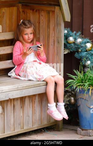 Une fille de 5 ans regardant des vidéos sur un téléphone portable Banque D'Images